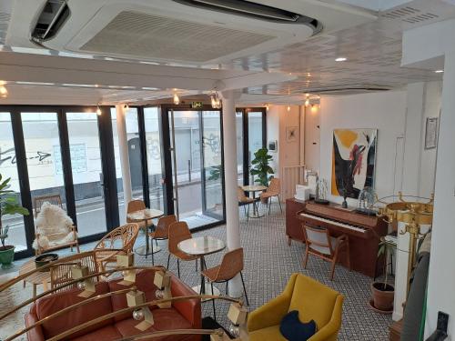 a room with a piano and chairs and tables at Hôtel Lucien in Paris