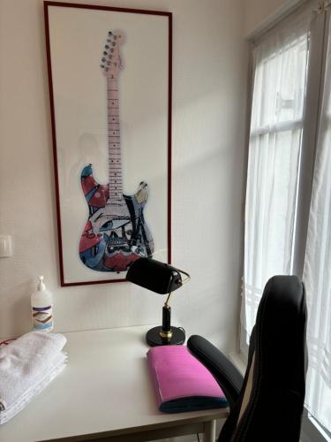 - un bureau avec une lampe et une guitare sur le mur dans l'établissement LA PETITE MAISON, à Le Perray-en-Yvelines