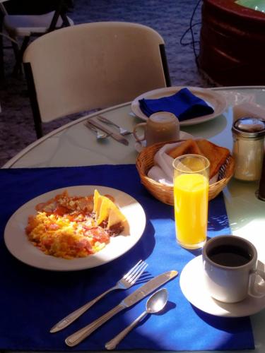 una mesa con un plato de desayuno y un vaso de zumo de naranja en Hotel Palacio de Moctezuma, en San Cristóbal de Las Casas