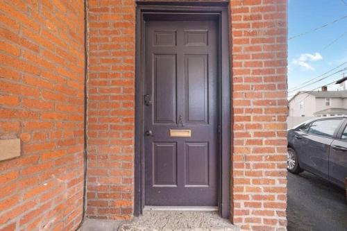 a black door on a brick building with a car at Housepitality - The Reichstag Suite - Modern in Columbus
