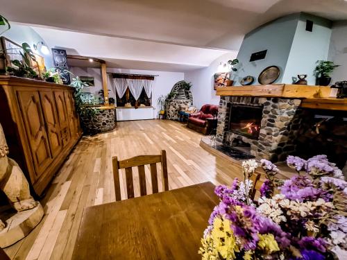 a living room with a fireplace and a table with flowers at Karkonoska Drewniana Chata in Kamienna Góra