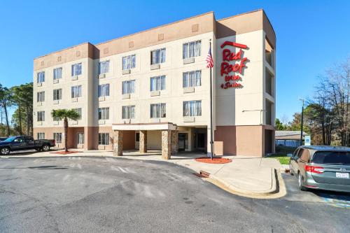 a building with a car parked in front of it at Red Roof Inn & Suites Fayetteville-Fort Bragg in Fayetteville