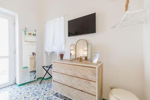 a bathroom with a dresser with a tv on a wall at Suite Villa Carolina in Capri