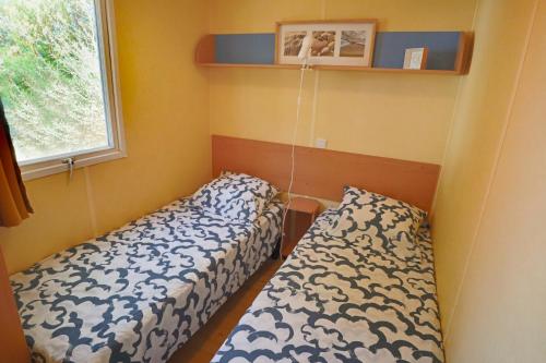 a bedroom with two beds and a window at Mobilhome LesPins YourHostHelper in Hyères