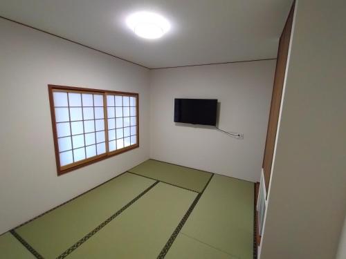 a room with a flat screen tv and a window at 政義の宿 in Matoba