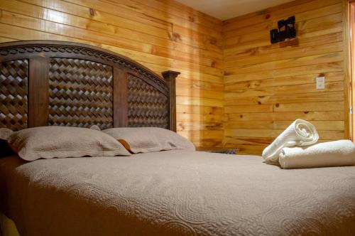 een bed in een kamer met houten wanden bij San José del Pacífico Familiar Camino al Cielo in El Pacífico