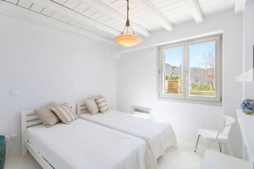 a white bedroom with two beds and a window at Island Villa Kon in Gavrio