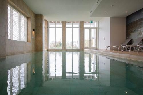 a swimming pool with green water in a building at Badhuis Dunes, Boulevard de Wielingen 2 in Cadzand