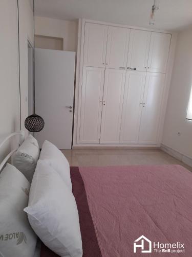 um quarto com armários brancos e uma cama com almofadas em Dimora em Chalkida