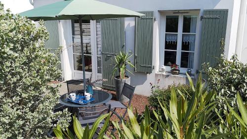 une table avec un parasol devant une maison dans l'établissement Maison PASSIFLORE, à Saint-Denis-dʼOléron