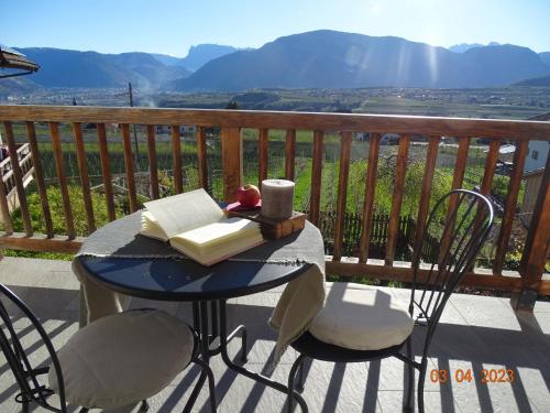een tafel met een boek en stoelen op een balkon bij Panoramaterrace, Wein & relax in Appiano Sulla Strada Del Vino