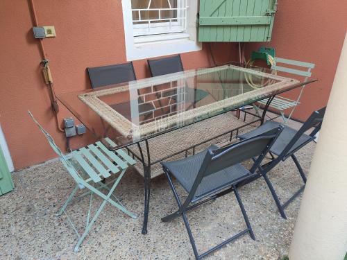 een glazen tafel en stoelen naast een gebouw bij la Seyne-sur-Mer, tamaris residence villa massada. in La Seyne-sur-Mer