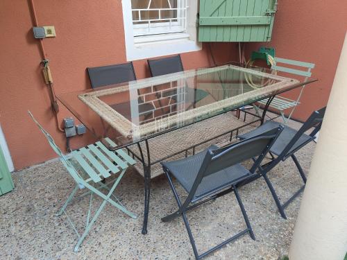 a glass table and chairs sitting next to a building at Villa Massada - déconnexion entre pins & mer in La Seyne-sur-Mer