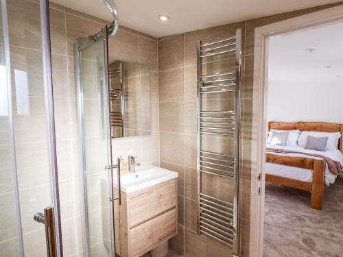 a bathroom with a shower and a sink and a bed at The Stables Merrydown in Axminster