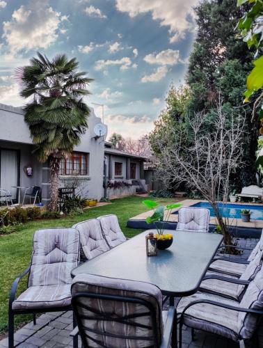 a patio with a table and chairs in a yard at Leana Hub Guest House in Potchefstroom