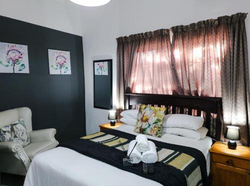 a hotel room with two beds and a chair at Leana Hub Guest House in Potchefstroom