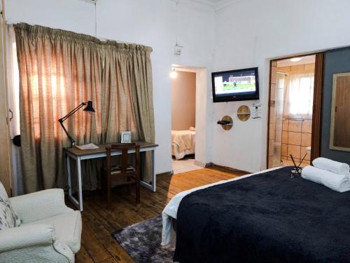 a bedroom with a bed and a couch and a television at Leana Hub Guest House in Potchefstroom