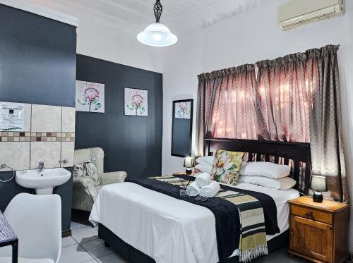 a bedroom with a bed and a sink and a bathroom at Leana Hub Guest House in Potchefstroom