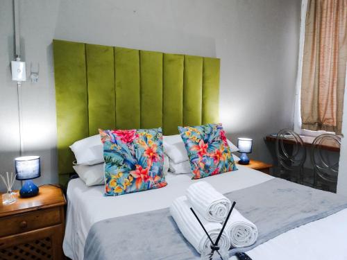a bedroom with a large bed with a green headboard at Leana Hub Guest House in Potchefstroom