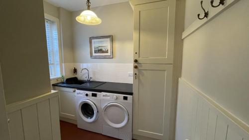 a laundry room with a washing machine and a sink at Tan Y Cytiau in Holyhead