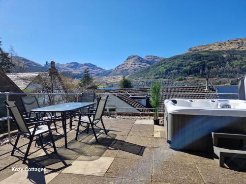 a table and a bath tub on a patio with mountains at No 2 Planetree in Lochgoilhead