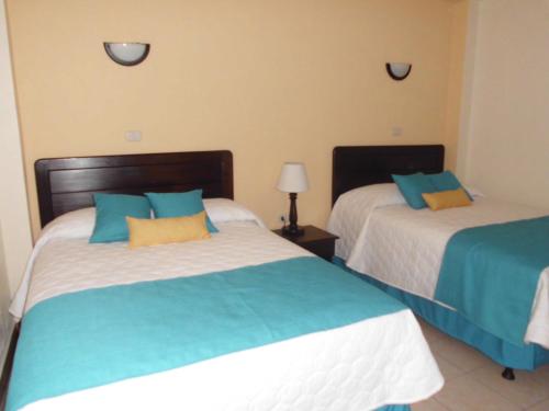 a bedroom with two beds with blue and white at Crysol Center Hotel in Chimaltenango