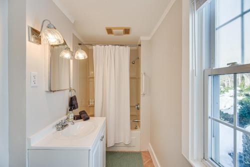 La salle de bains blanche est pourvue d'un lavabo et d'une fenêtre. dans l'établissement Idyllic Portsmouth Vacation Rental 3 Mi to Beach, à Portsmouth