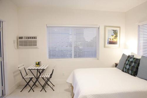 a white bedroom with a bed and a table and chairs at Apt 1 Miami Designer Studio in the Upper East-Side in Miami