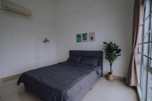 a bed in a white room with a plant at Mount Austin Manhanttan Sovo by Cactus Homestay in Johor Bahru