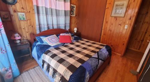 a bedroom with a bed in a wooden room at CASA DE HUÉSPEDES JEM in Bucalemu