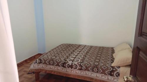 a small bedroom with a bed with a brown blanket at Hospedaje Catalina in Pisac