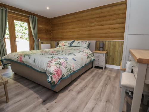 1 dormitorio con 1 cama y pared de madera en Redwood Lodge, en Ellesmere