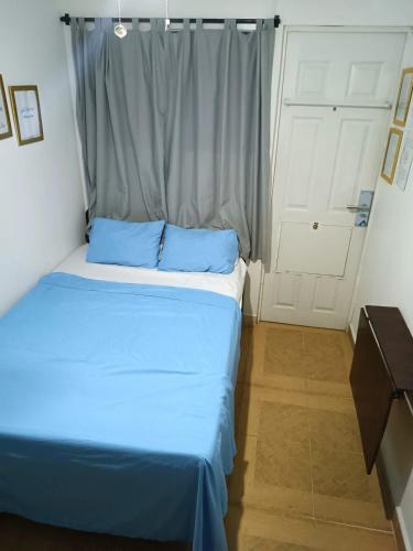 Un dormitorio con una cama con sábanas azules y una ventana. en Orison Hostels Managua, en Managua