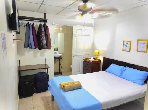 Schlafzimmer mit einem Bett mit blauer Bettwäsche und einem Deckenventilator in der Unterkunft Orison Hostels Managua in Managua