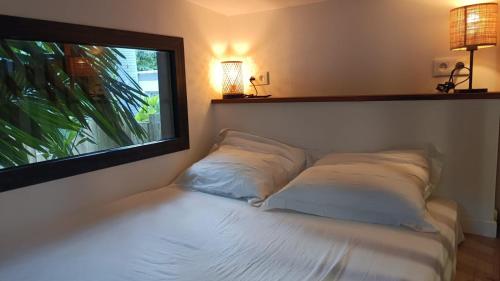 - un lit avec deux oreillers assis à côté d'une fenêtre dans l'établissement Tiny house au lagon, à Saint-Paul