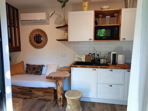 eine Küche mit weißen Schränken und einem Tisch im Zimmer in der Unterkunft Tiny house au lagon in Saint-Paul