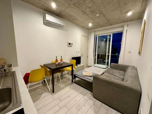 a living room with a couch and a table with yellow chairs at Heart of the Paceville Modern Apartment! in St. Julianʼs