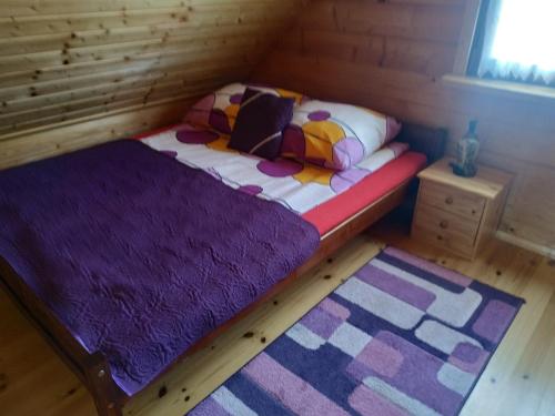 a small bed in a wooden room with two rugs at Domek letniskowy OAZA in Ryn