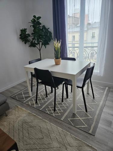 a white dining room table with chairs and a potted plant at appartement 93 proche stade de France in Saint-Denis