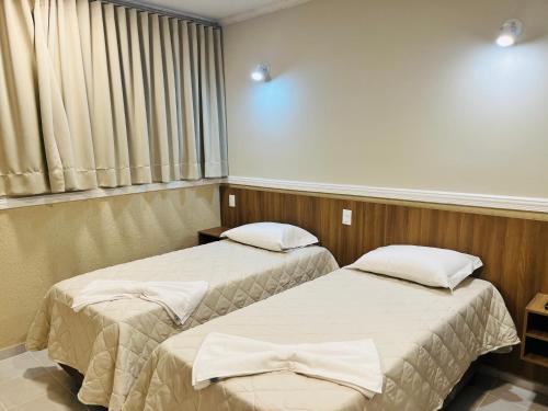 twee bedden in een ziekenhuiskamer met een raam bij Hotel Estoril Garden & Restaurante in Registro