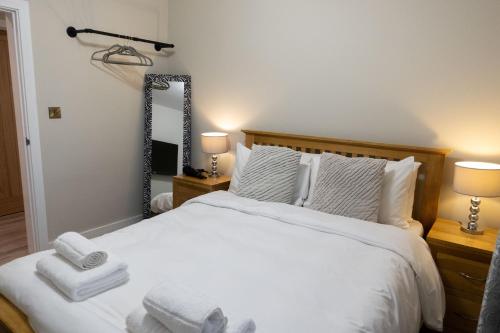 赫里福德的住宿－Contemporary new build with parking & garden in central location，卧室配有一张带两盏灯和镜子的白色床。