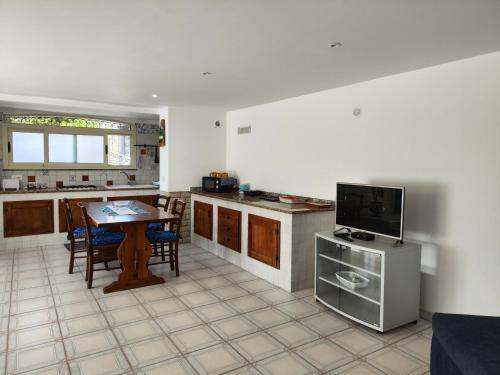 a kitchen with a table and a tv in it at Villa Vera in Fontane Bianche