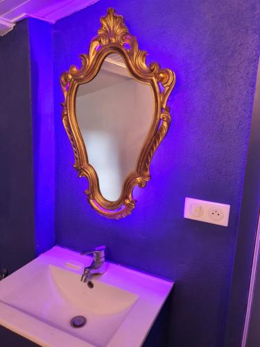 La salle de bains est pourvue d'un lavabo et d'un miroir sur un mur violet. dans l'établissement Bastide gecko doré, à Cotignac