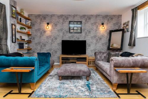 a living room with blue couches and a tv at The Coach House in Cheltenham
