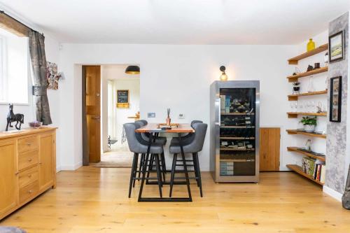 切爾滕納姆的住宿－The Coach House，厨房配有桌子、凳子和冰箱。