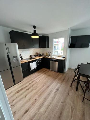 une cuisine avec des armoires noires et un plancher en bois dans l'établissement Beautiful flat (metro 8) 10min to paris city center, à Maisons-Alfort