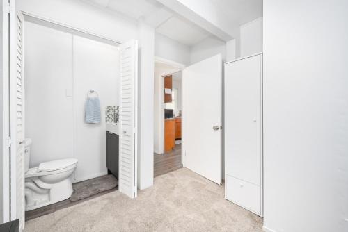 a white bathroom with a toilet and a corridor at 2 Bedroom steps to the beach in West Newport in Newport Beach