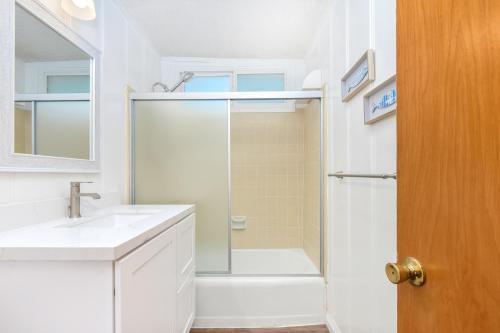 uma casa de banho branca com um chuveiro e um lavatório. em Upstairs 2 Bedroom Home with Ocean Views on 65th St em Newport Beach