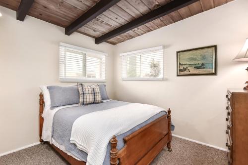 um quarto com uma cama e duas janelas em West Newport Duplex on the Sand with Patio-Sleeps 12 em Newport Beach