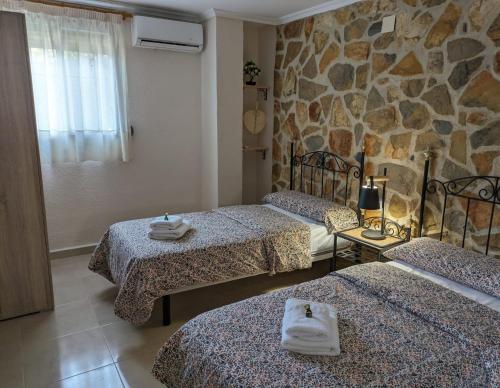 a room with three beds and a stone wall at Chalet con piscina, barbacoa y jacuzzi en Valencia in Turís